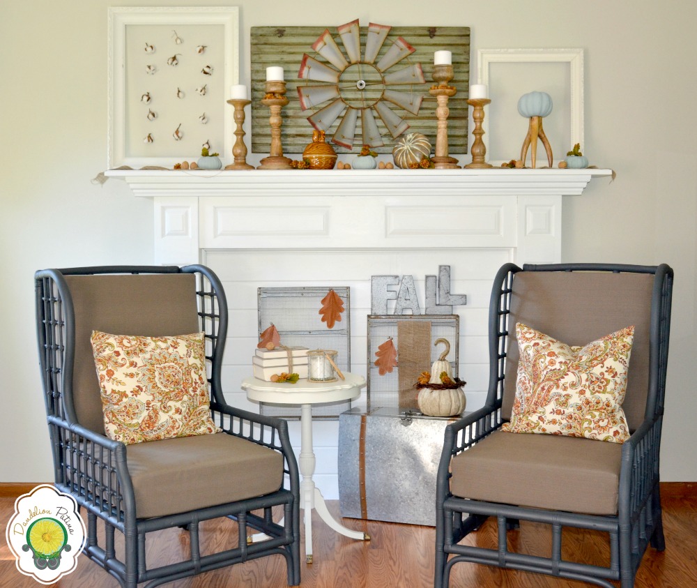 White fireplace mantel decorated with fall leaves and two chairs flanking the fireplace.