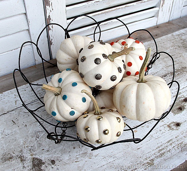 Little white pumpkins decorated in a wire basket on the front porch.