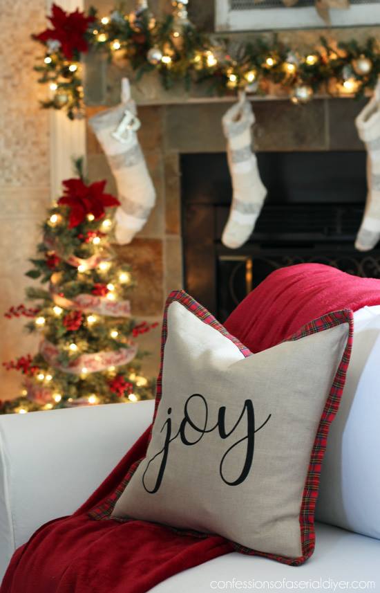 A red plaid and white pillow with the words joy on it.