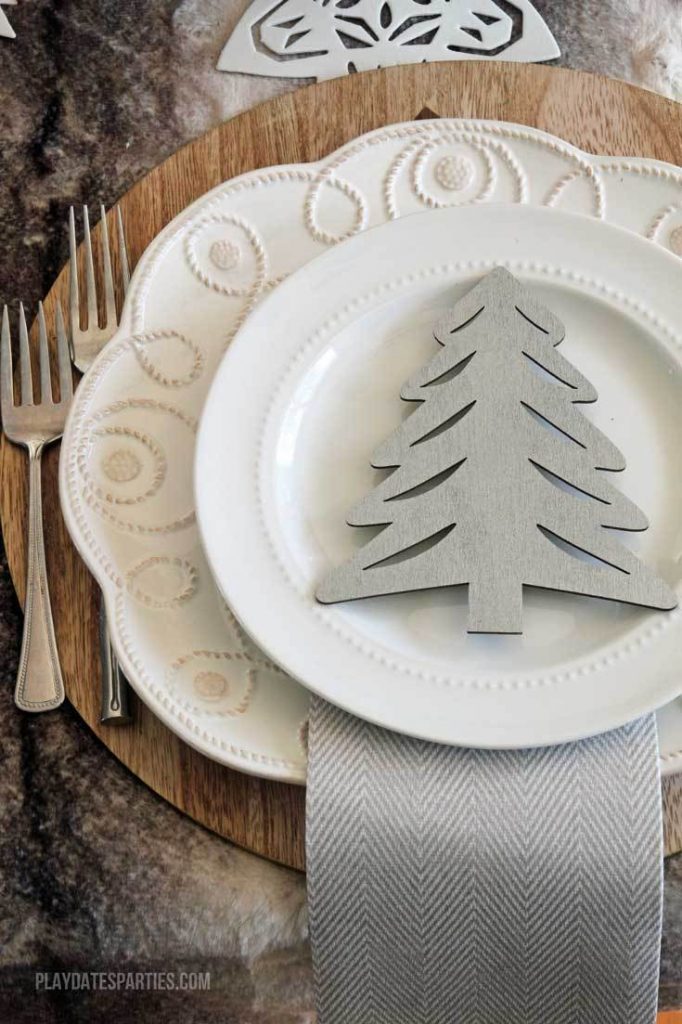A cut out wooden tree on a white plate setting.